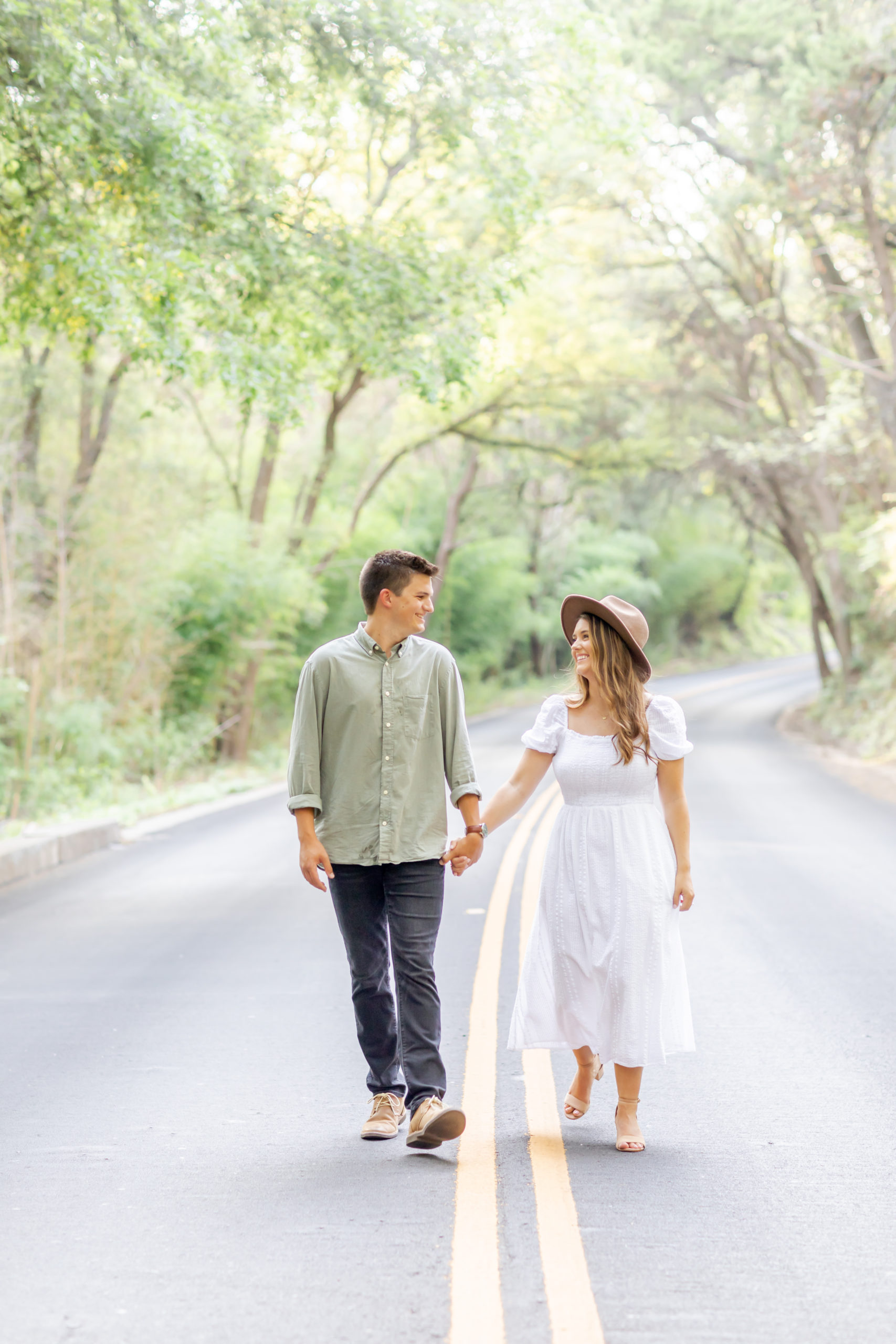 walking hand in hand down road engagement photo